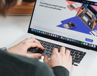 Eine Person tippt auf einem MacBook Pro und arbeitet an einem Online-Shop, der auf dem Bildschirm geöffnet ist.